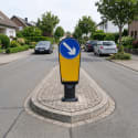 Verkehrsinselbake mit blauem Pfeilschild nach rechts auf einer Verkehrsinsel in einer Wohnstraße