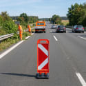 Klappbake SPEEDY Absperrung auf Autobahn mit Straßenarbeitern und Fahrzeugen im Hintergrund