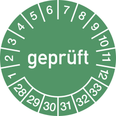 Grüne Prüfplakette mit der Aufschrift geprüft, Zahlen von 1 bis 12 für Monate und 28 bis 33 für Jahre