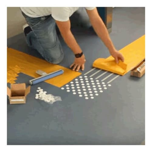 Person verlegt taktile Leitstreifen mit Express-Verlegeschablone auf Boden
