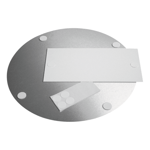 Weiße Schaumstoffklebepunkte auf runder Metallfläche und rechteckigem Papier