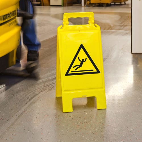 Gelber Warnaufsteller mit Warnzeichen für Rutschgefahr auf glattem Boden