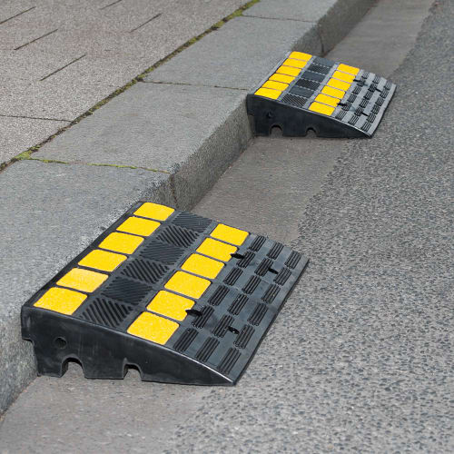 Bordsteinrampe MOVE aus Kunststoff mit gelben rutschfesten Markierungen an einem Gehweg