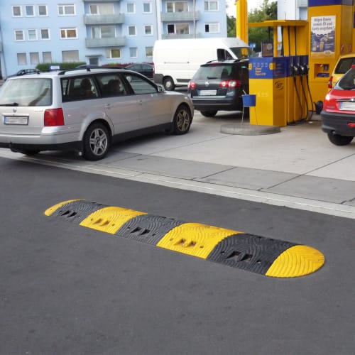 Richtstange für Fahrbahnschwelle TOPSTOP aus Kautschuk in schwarz und gelb auf Asphalt vor einer Tankstelle