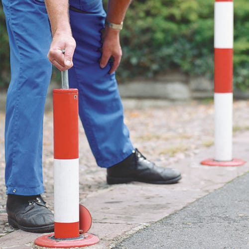 Absperrpfosten PARATlift versenkbar rot weiß zum Einbetonieren mit Person in blauer Hose