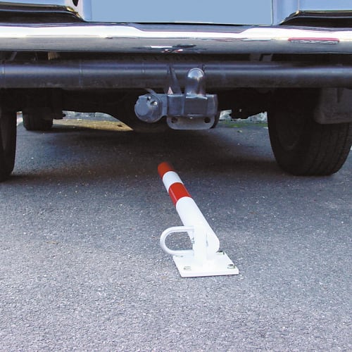 Klappbarer Absperrpfosten SCHUPO in weiß und rot auf Asphalt vor einem geparkten Fahrzeug