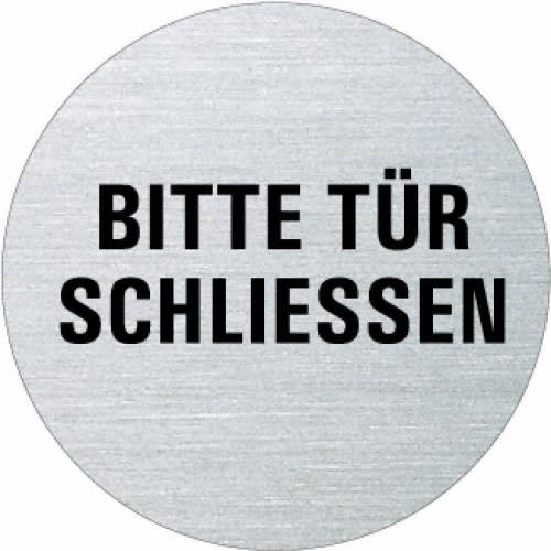 Rundes Textschild mit der Aufschrift Bitte Tür schließen in schwarzer Schrift auf silbernem Hintergrund