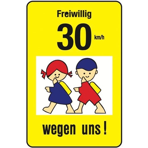 Gelbes Schulwegschild mit der Aufschrift Freiwillig 30 km/h wegen uns und zwei Kindern, die zur Schule gehen