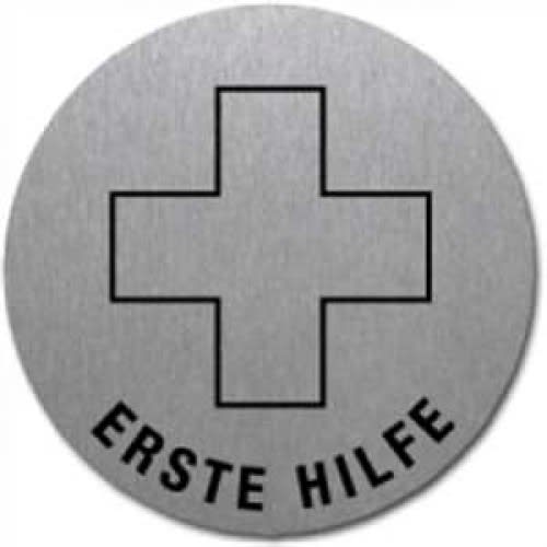Rundes Textschild mit schwarzem Erste Hilfe Kreuz und Schriftzug Erste Hilfe auf grauem Hintergrund