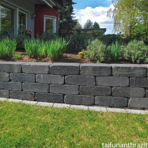 Beton-Mauerstein Retumbo als Gartenmauer mit grünen Pflanzen und Rasen im Hintergrund