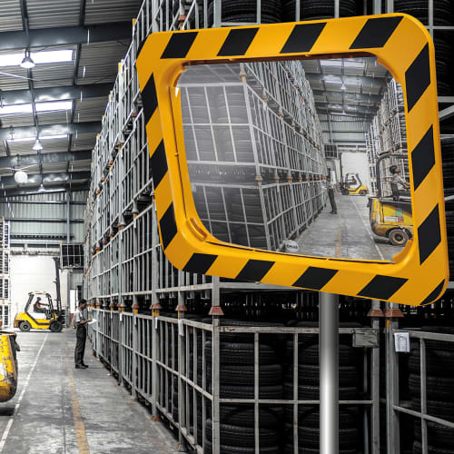 Industriespiegel gelb schwarz zur Überprüfung von 2 Richtungen in Lagerhalle mit Regalen und Gabelstaplern