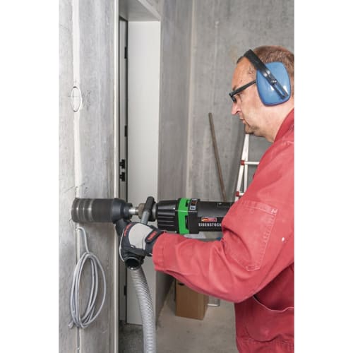 Handwerker mit Schutzbrille und Gehörschutz bohrt mit Diamant Trockenkernbohrmaschine EIBENSTOCK in Betonwand