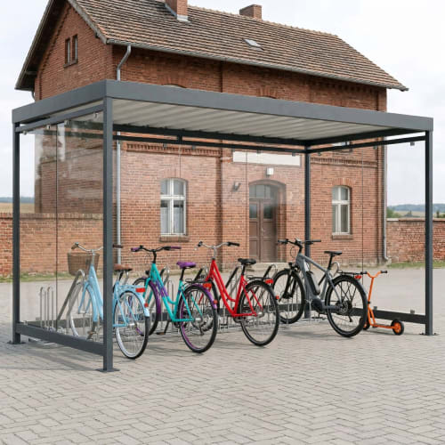 Fahrradüberdachung Köln Bike Professional K4 b/b mit mehreren Fahrrädern und einem Roller vor einem Backsteingebäude