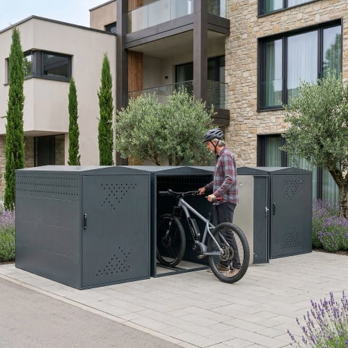 Fahrradgarage BikeBox 1 G XL aus Metall mit geöffnetem Fach, in dem ein Mann mit Fahrradhelm ein E-Bike abstellt, moderne Wohnhausfassade im Hintergrund