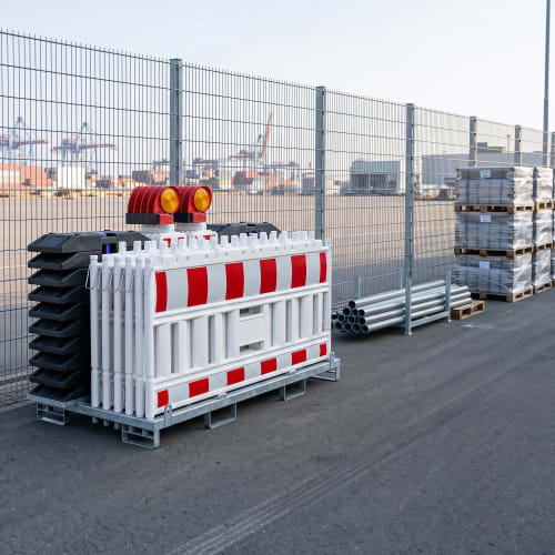 Absperr-Set Trio NOXPLUS mit Schrankenzäunen, Baken, Leuchten und Fußplatten auf einem Industriehof