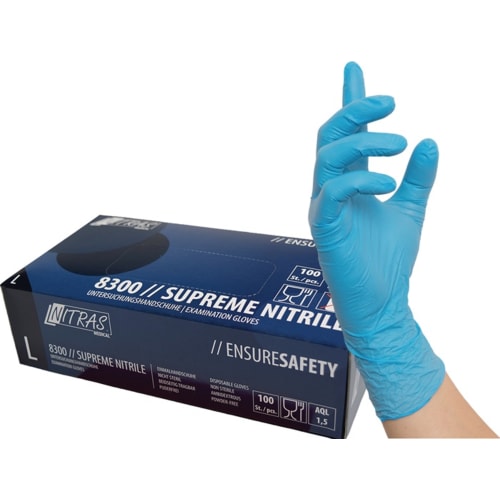 Hand mit blauem NITRAS Supreme Nitrile Einweghandschuh vor Packung mit 100 Stück