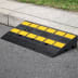 Bordsteinrampe TEX aus schwarzem Material mit gelben rutschfesten Markierungen an einer Bordsteinkante
