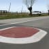 Fahrbahnschwelle Berliner Kissen GAMMA oval in rot und weiß auf Asphalt mit Auto und Bäumen im Hintergrund
