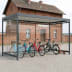 Fahrradüberdachung Köln Bike Professional K4 b/b mit mehreren Fahrrädern und einem Roller vor einem Backsteingebäude