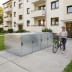 Fahrradgarage BikeBox 1 Basic aus Metall vor einem Wohnhaus mit Frau und Fahrrad