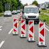 Vier TL Klappbaken Typ 750 REFLEX mit roten und weißen diagonalen Streifen auf einer Straße vor einem weißen Fahrzeug mit Warnleuchte