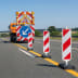 Kunststoff-Sicherheitsbake LIGHT Typ 40 mit rot-weißen diagonalen Streifen auf einer Straße bei Baustelle