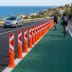 Flexibake flexible orange traffic delineator posts with red and white reflective arrows separating bike lane from road with cyclists and car