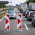 Klappbake mit rutschfestem Standfuß auf einer Autobahn mit Verkehrsstau und Polizeiauto im Hintergrund
