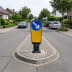 Verkehrsinselbake mit blauem Pfeilschild nach rechts auf einer Verkehrsinsel in einer Wohnstraße
