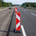 Klappbake SPEEDY mit großem Fuß auf einer Autobahnbaustelle mit Walzenfahrzeug im Hintergrund