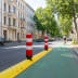 Poller LEITBOY rote und weiße Verkehrspoller auf gelber Trennvorrichtung neben grünem Fahrradweg in städtischer Straße