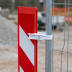 Verbindungsklemme aus Kunststoff befestigt rote und weiße Warnbake an Metallzaunpfosten auf Baustelle