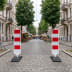 Sperrbake Bake Typ S geblockt mit rot-weißen Streifen auf gepflasterter Straße in urbaner Umgebung