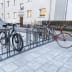 Fahrradständer Epsilon Plus mit mehreren Fahrrädern auf einem gepflasterten Bürgersteig vor einem Wohngebäude