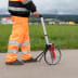 Person in orange Warnschutzkleidung misst mit NESTLE Messrad MR-21 auf Asphaltweg