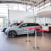 Gurtabsperrpfosten Beltrac Classic mit rotem Gurt in einem Autohaus neben einem grauen SUV