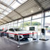 Gurtabsperrpfosten Beltrac Extend mit rotem Absperrband in einem Autohaus mit weißen und schwarzen Autos