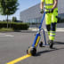Markiergerät PROline-paint in Gebrauch zum Ziehen einer gelben Linie auf Asphalt, Person in Warnschutzkleidung